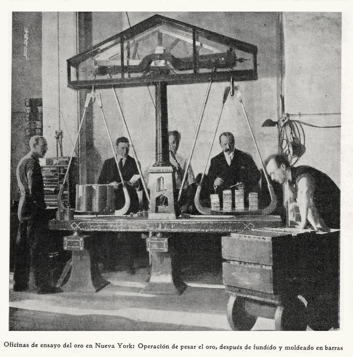 Four men around a large beam balance at the New York gold assay office in 1917, with gold ingots on both pans.